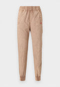 Beige Jogginghosen mit elastischem Bund und gekräuselter Textur, ausgestattet mit gerippten Bündchen und Seitentaschen. Enthält ein kleines rotes Logodetail.