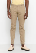 Beige Chinos mit schmalem Schnitt, aus Baumwolle. Mit einem Knopfverschluss, Vorderaschen und umgeschlagenen Säumen. Kombiniert mit hellen Slippern.
