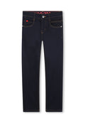 Dunkelblaue Jeans aus Denim mit kontrastierenden gelben Nähten, fünf Taschen und einem silbernen Knopfverschluss. Verfügt über ein rotes Markenetikett am Bund.