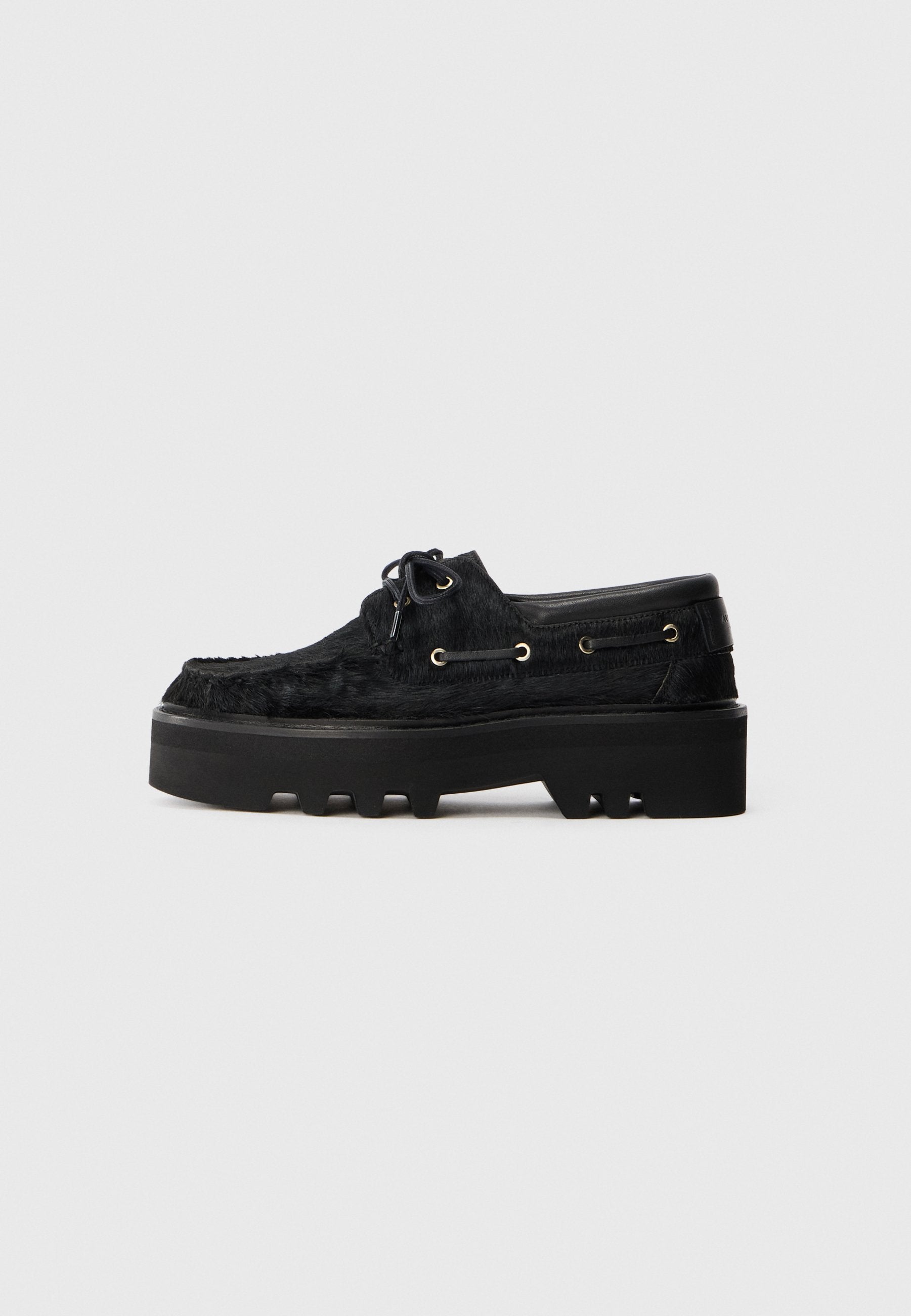 Schwarze Schuhe mit einer klobigen Plateausohle und einem strukturierten Pelzfinish. Verfügt über runde Schnürsenkel, goldene Ösen und eine strukturierte Gummisohle.