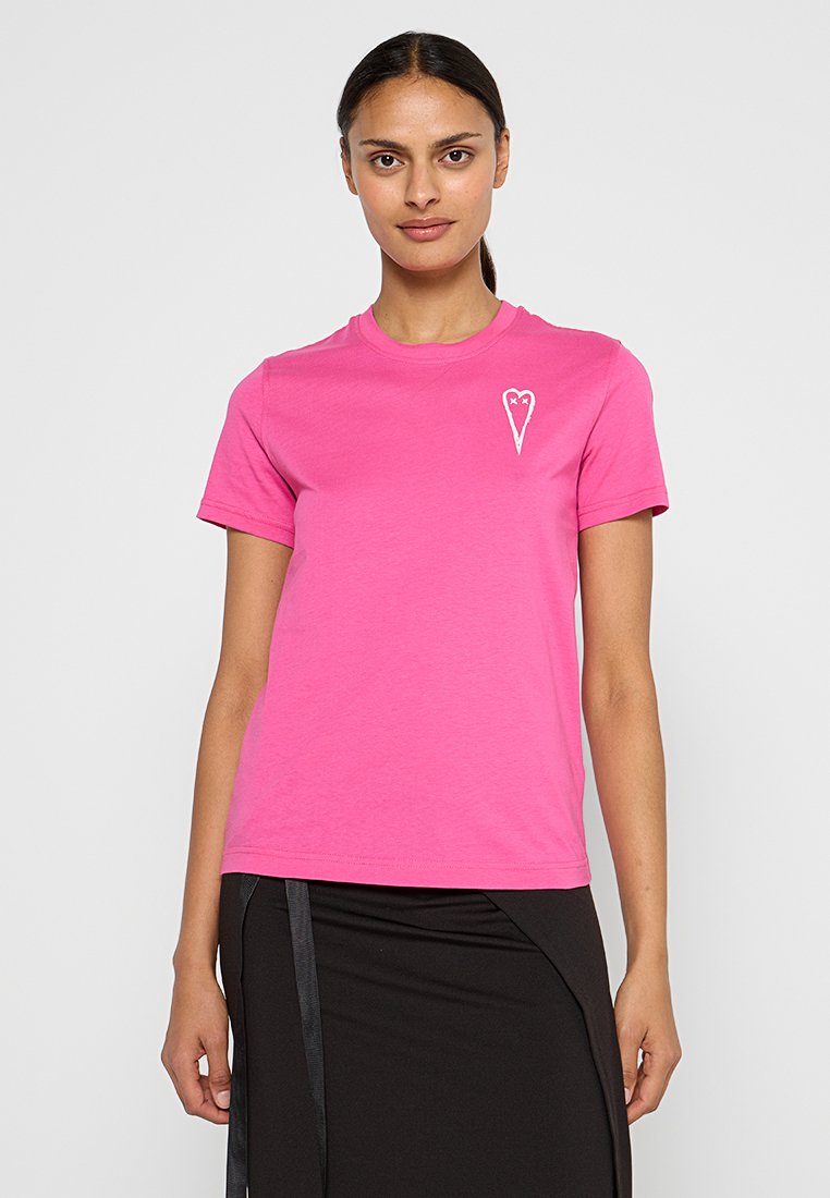 Rosa kurzärmliges T-Shirt aus Baumwolle mit einem weißen Herz-Graphic auf der linken Brustseite. Einfaches, geradliniges Design.