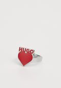 Silberring mit einer auffälligen roten Herzform und dem Wort "HUGO" in fetten, erhabenen Buchstaben oben. Glatte Oberfläche mit glänzenden Akzenten.