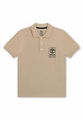 Beige Poloshirt mit kurzen Ärmeln, drei Knöpfen und Timberland-Logo-Patch auf der linken Brust.