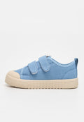 Hellblauer Canvas-Sneaker mit beiger Gummisohle und Zehenkappe, ausgestattet mit zwei Klettverschlüssen und einer Schlaufe an der Ferse.