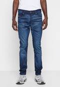 Dunkelblaue Denim-Jeans mit Slim-Fit, ausgestattet mit einem Fünf-Taschen-Design und einem Knopfverschluss, getragen mit grauen Sportschuhen.