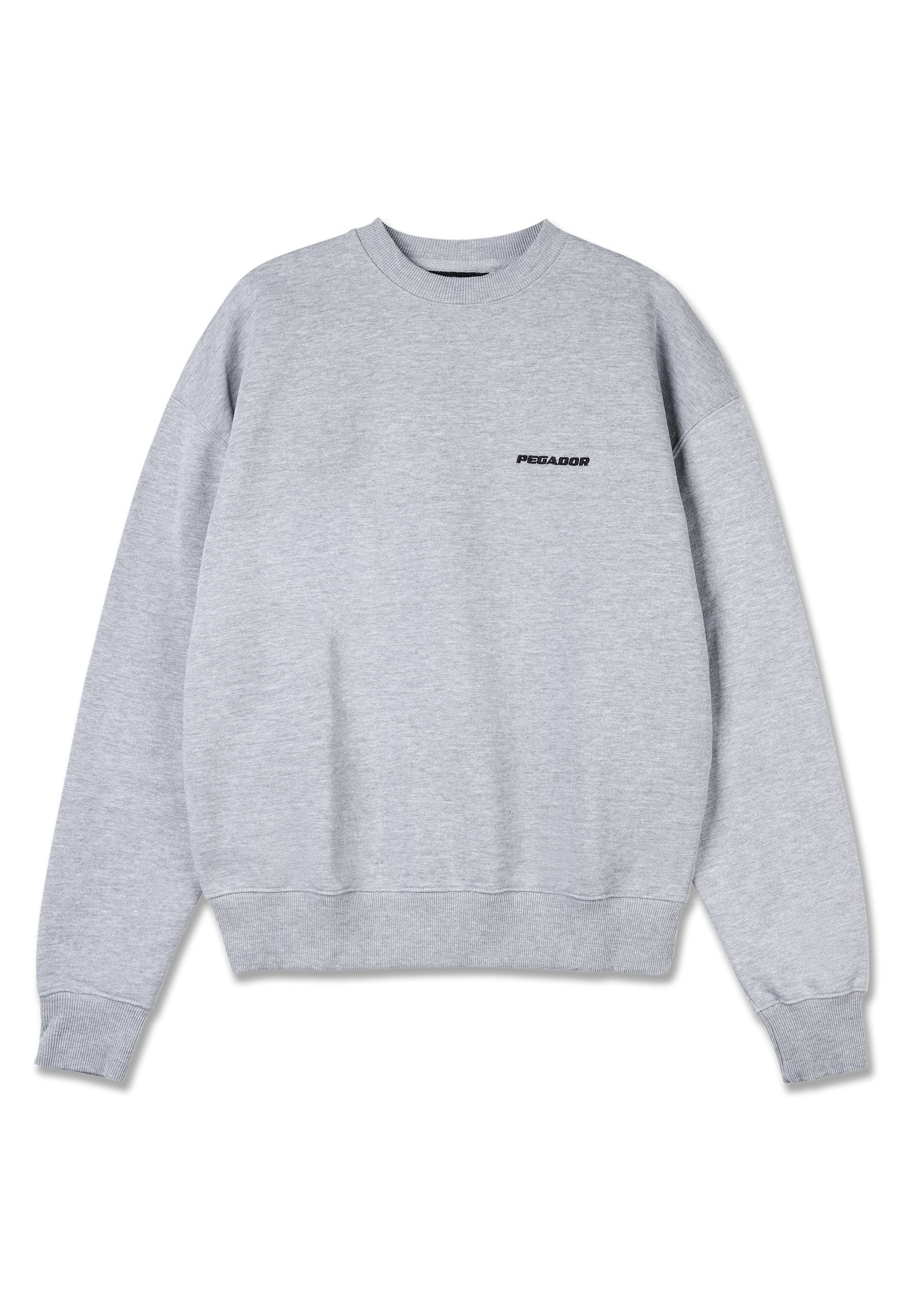 Grauer Pullover mit langen Ärmeln, gerippten Bündchen und Saum. Auf der oberen linken Seite der Vorderseite befindet sich ein schwarzes Logo "PEGADOR". Weicher Stoff.