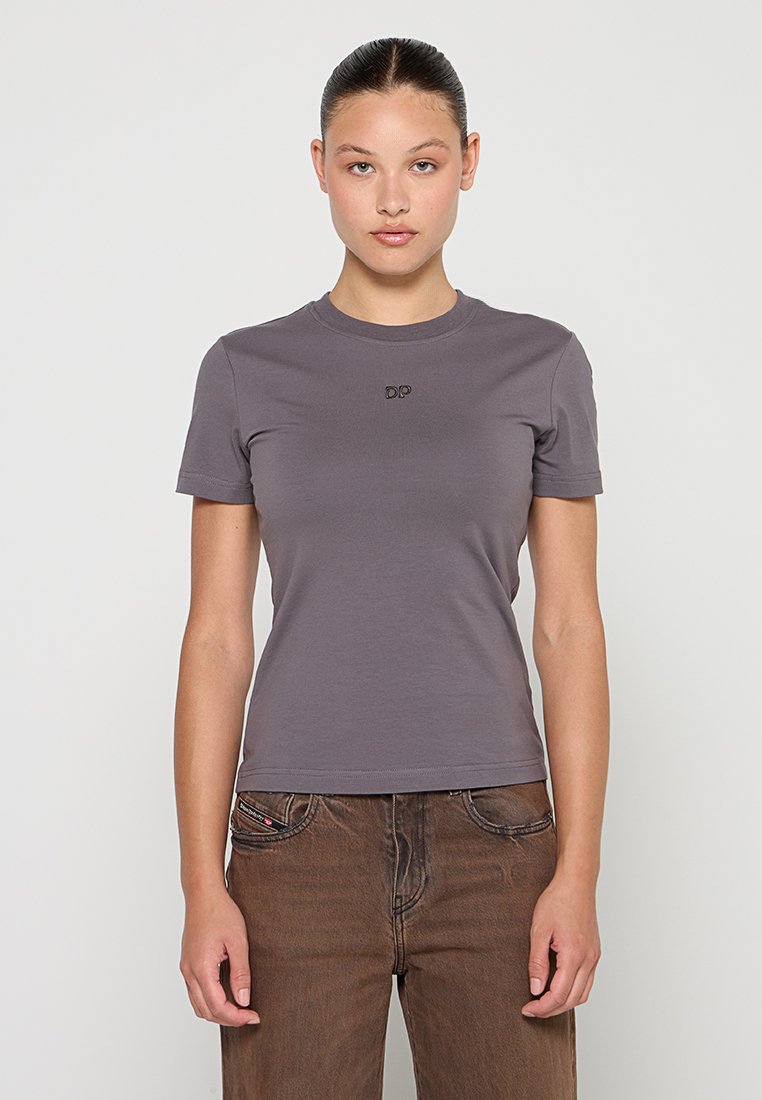 Graues Baumwoll-T-Shirt mit rundem Halsausschnitt, kurzen Ärmeln und einem kleinen gestickten Logo auf der Brust, kombiniert mit braunen Jeans.