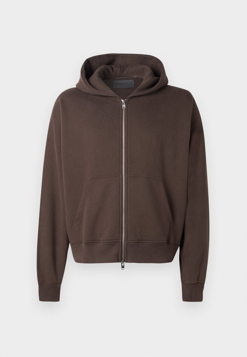 Braune Zip-Hoodie aus weichem Material, ausgestattet mit einer geräumigen Kapuze, einer frontalen Kängurutasche sowie gerippten Bündchen und Saum.