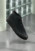 Schwarzer Sneaker in hoher Schnittform mit Obermaterial aus Canvas, rundem Zehenbereich und tonalen Schnürsenkeln. Verfügt über eine Gummisohle und ein kleines rotes Akzent am Absatz.