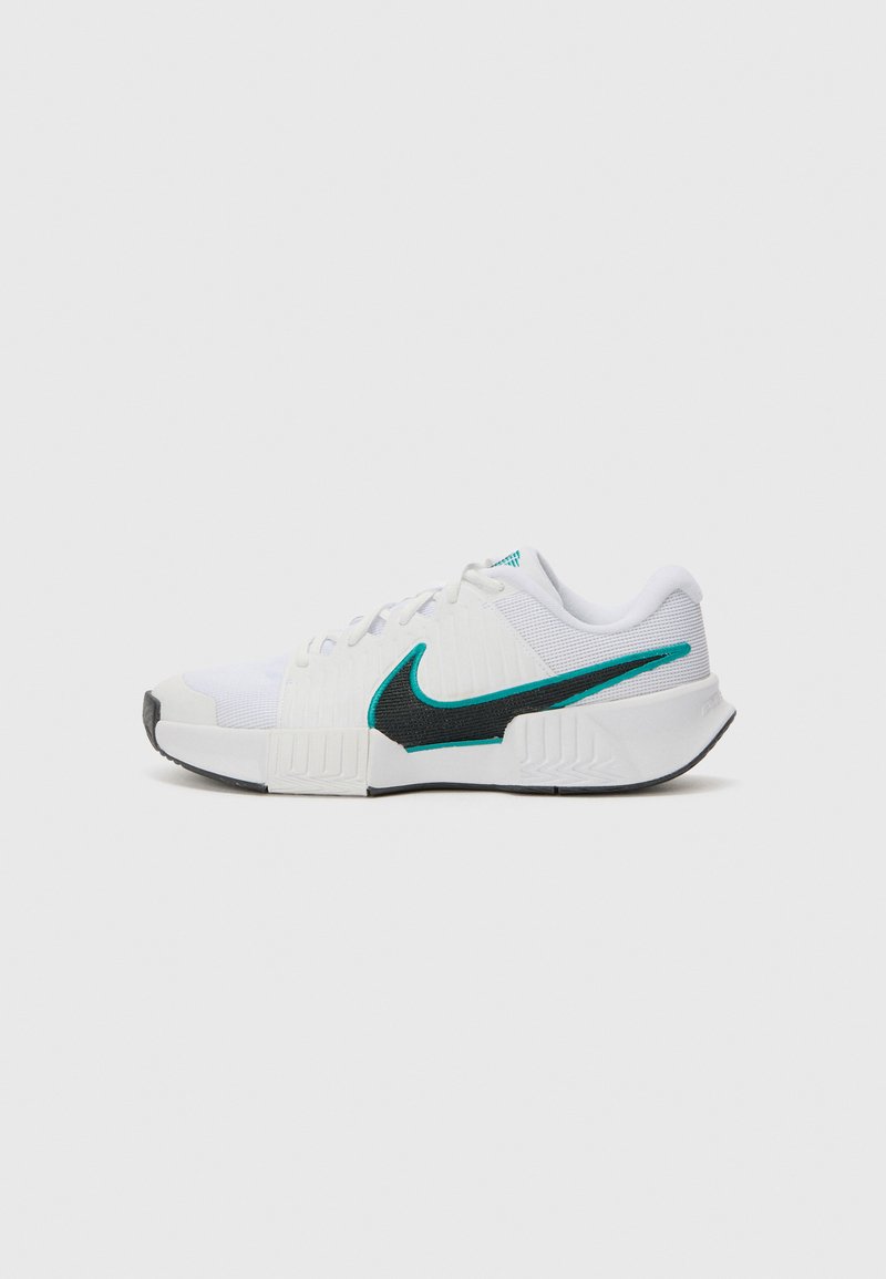 Weißer Sportschuh mit strukturiertem Mesh-Obermaterial, schwarzer Gummisohle und türkisfarbenem Nike-Swoosh-Akzent. Verfügt über Schnürsenkel und gepolsterten Kragen.