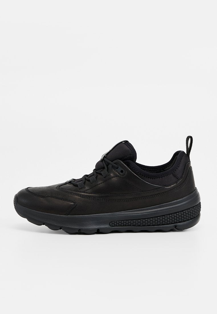 Schwarzer Low-Top-Sneaker mit Schnürverschluss, gepolstertem Kragen, strukturiierter Sohle und Zuglasche an der Ferse, seitlich betrachtet.