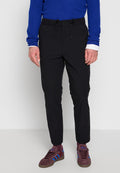 Schwarze tapered Jogginghosen mit elastischem Bund und Kordelzug. Kombiniert mit einem blauen Pullover und kastanienbraunen Sneakers mit blauen Streifen.