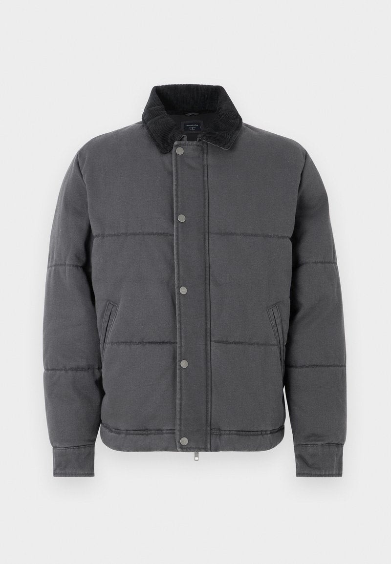 Graue Steppjacke mit gestepptem Design, Cordkragen, Druckknöpfen, Seitentaschen und gerippten Bündchen, aus einem glatten, strukturierten Material.