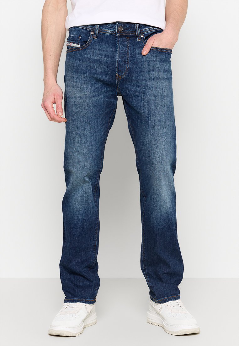 Blaue Jeans aus Denim mit geradem Bein. Merkmale sind dezentes Verblassen und Gebrauchsspuren, Fünf-Taschen-Design und ein Metallknopfverschluss.