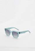 Quadratische blaue transparente Sonnenbrille mit dunklen Verlaufs-Gläsern, leicht schräg auf weißem Hintergrund gezeigt.