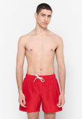 Rote Badeshorts mit elastischem Bund und weißem Kordelzug. Aus leichtem Stoff gefertigt, mit einem schlichten Design und einem kleinen Logo.