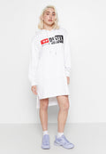 Frau, die ein weißes Diesel-Hoodie-Kleid mit Fronttasche trägt, steht mit helllila Sneakers und weißen Socken vor einem schlichten Hintergrund.
