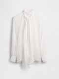 Weiße Bluse mit hohem Kragen, vorne fließend, lange Ärmel und geknöpfte Manschetten. Hergestellt aus einem leichten, transparenten Stoff.