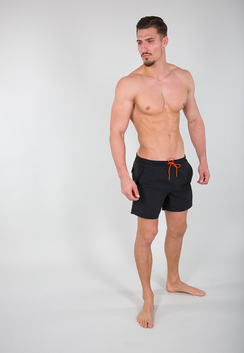 Schwarze Badetäschchen mit elastischem Bund und orangefarbigem Kordelzug, mit einem schlichten Design, ohne Muster und aus leichtem Material.