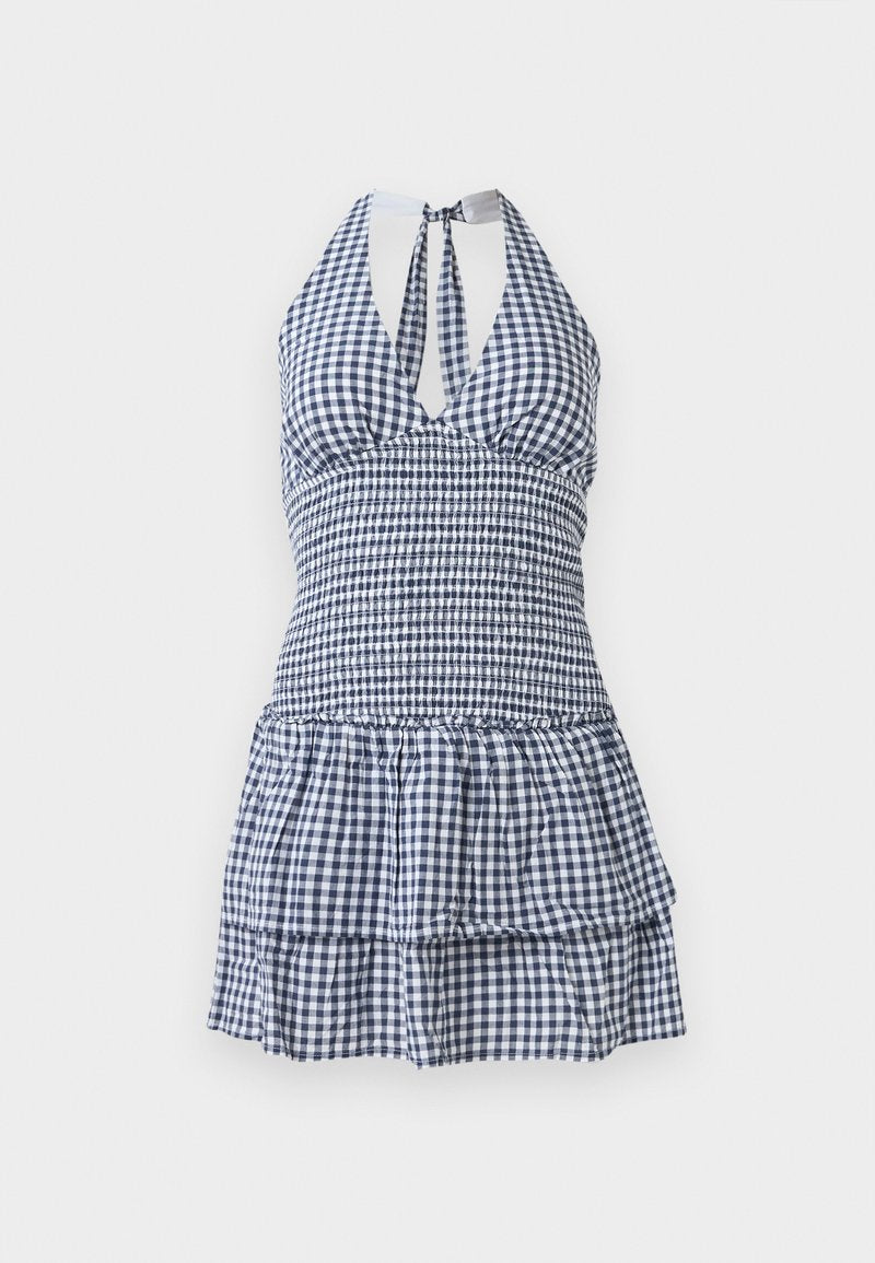 Kariertes Sommerkleid in Marineblau und Weiß, mit tailliertem Oberteil, Halterneck, offenem Rücken und einem gestuften, volantrüschierten Saum.