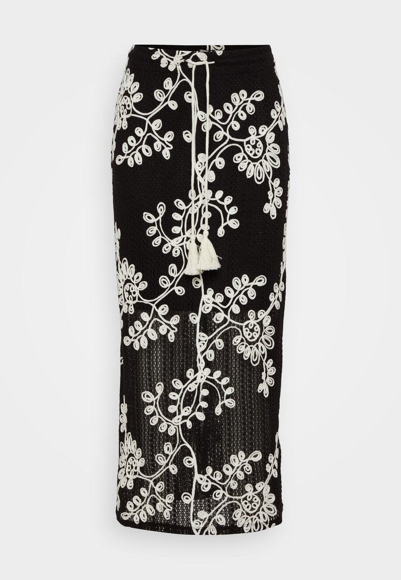 Schwarzer Strickrock mit aufwendiger weißer Blumenstickerei, verstellbarem Zugband mit Quaste und figurbetontem Schnitt.