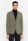 Olivgrüner Blazer mit schlankem Design, einreihigen Knöpfen, Reverskragen und zwei vorderen Taschen. Getragen über einem schwarzen Rollkragenpullover.