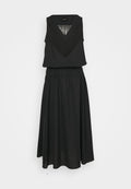 Schwarzes ärmelloses Kleid mit V-Ausschnitt, das Fransen details am Oberteil, einen elastischen Taillenbund und einen fließenden, knielangen Rock hat.