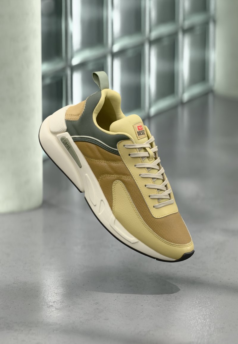 Sneaker mit einer Mischung aus gelbem und beigem Mesh und Leder, mit einem grünen Akzent, Schnürdesign und einer strukturierten Sohle.