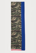 Strickschal mit einem Camouflage-Muster in Grün und Beige, einer einfarbigen blauen Seite und einem roten Akzent am unteren Rand mit einem Logo-Detail.