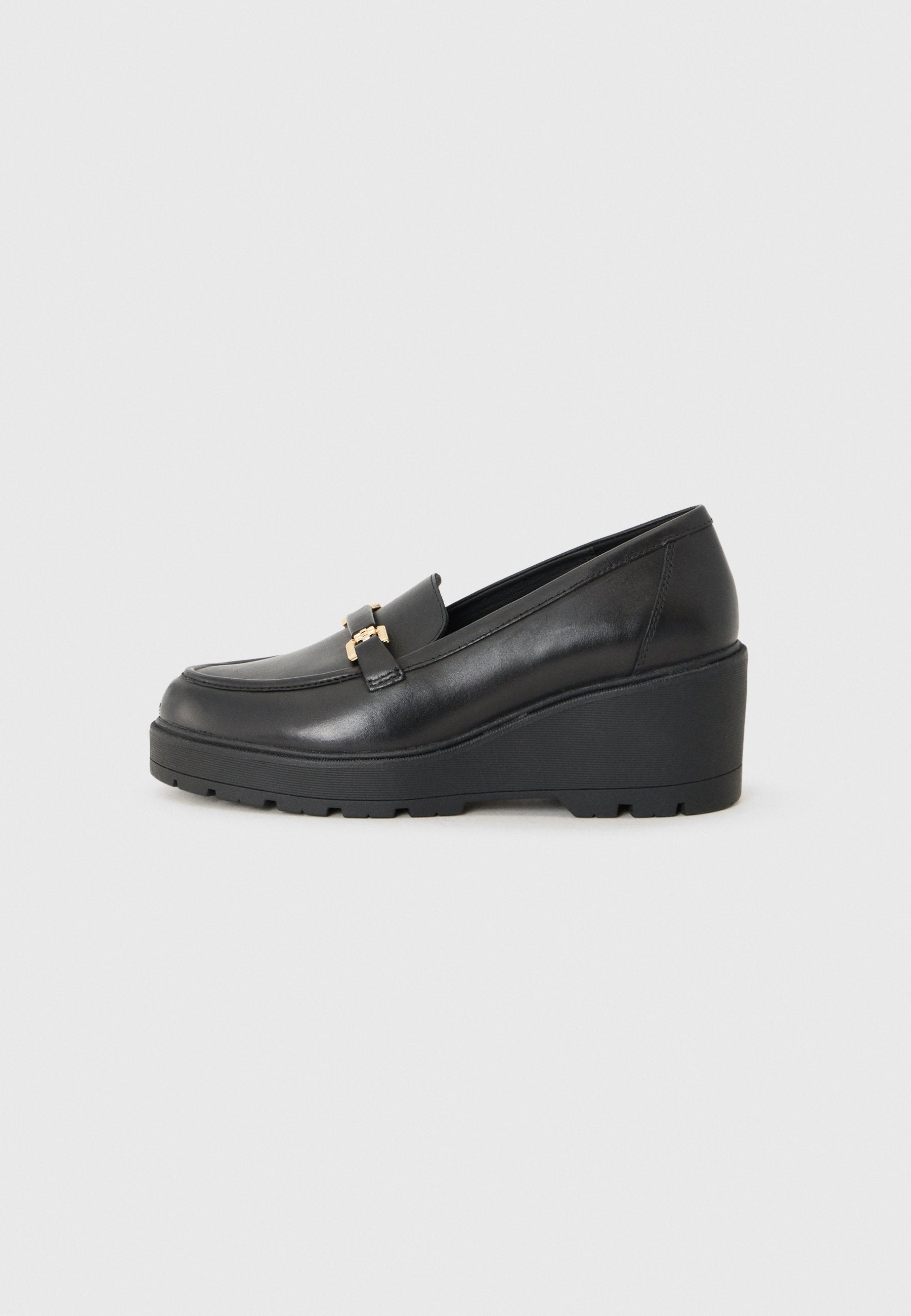 Schwarze Keillederschuhe aus glattem Leder mit abgerundeter Zehenpartie, die an der Vorderseite ein dekoratives Detail aus goldfarbigem Metall aufweisen.