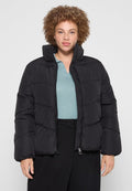 Schwarze Steppjacke mit Reißverschluss, gestepptem Design, hohem Kragen und gerippten Bündchen. Getragen über einem hellblauen strukturierten Oberteil.