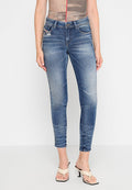 Schlanke blaue Denim-Jeans mit leichter Abnutzung, fünf Taschen und einem mittelhohen Bund. Getragen mit beigen, sandalettenartigen Schuhen.