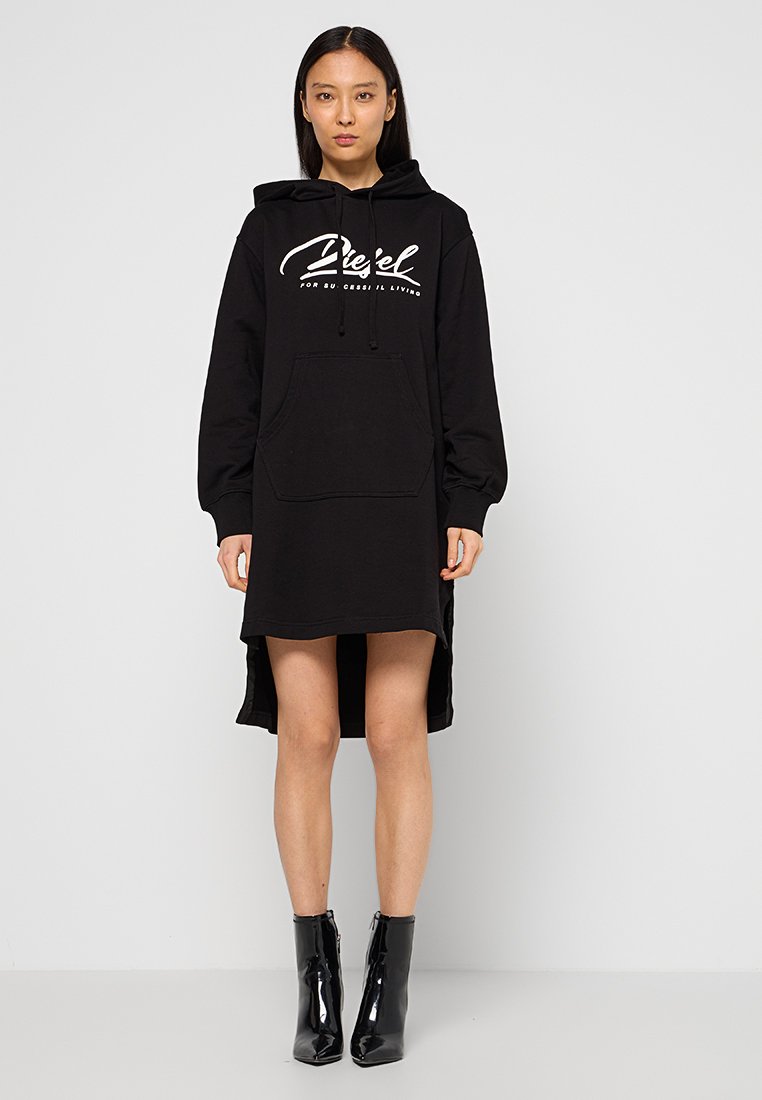 Schwarzes Hoodie-Kleid mit langen Ärmeln, vornem Taschen und seitlichen Schlitzen. Mit weißem grafischem Text auf der Brust. Der Stoff scheint weich und strukturiert zu sein.