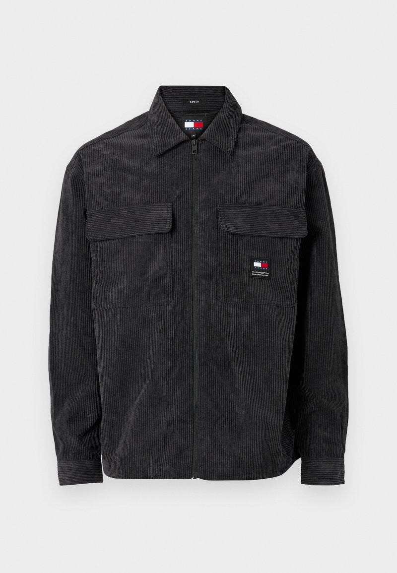 Schwarze Samtjacke mit einem Reißverschluss vorne, zwei Brusttaschen und einem kleinen Logo auf der linken Seite. Mit einem kragenförmigen Ausschnitt und gerippten Bündchen.