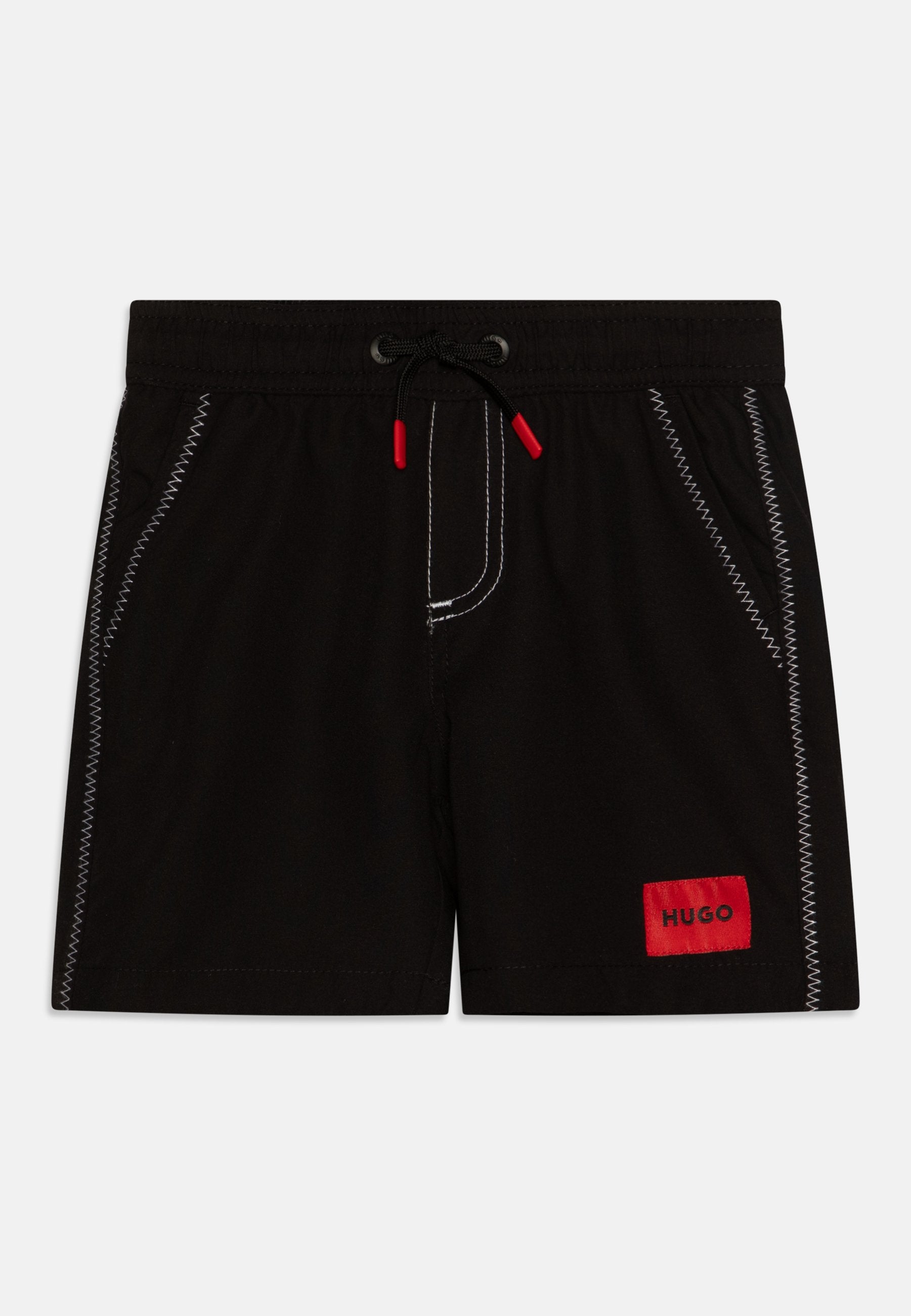 Schwarze Schwimmshorts mit weißer Naht, elastischem Bund und verstellbarem Kordelzug. Enthält ein rotes Etikett mit "HUGO" an der Seite.