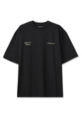 Schwarzes T-Shirt mit kurzen Ärmeln, links auf der Brust mit dem Schriftzug „Moments To Memories“ und rechts auf der Brust mit „PEGADOR“ in hellbeiger Schrift.