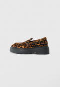 Loafer-Schuh mit Obermaterial in braunem und schwarzem Leopardenmuster und dicker schwarzer Plateausohle auf weißem Hintergrund.