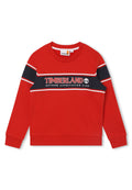 Roter Baumwollpullover mit rundem Halsausschnitt, langen Ärmeln und einem kontrastierenden marineblauen Band mit dem Logo und Schriftzug "TIMBERLAND". Gerippte Bündchen und Saum.