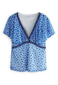 Blaue Blumenshirtbluse mit kurzen Rüschensäumen, V-Ausschnitt, verziert mit marinefarbenen Abschlüssen und kleinen Blumenmustern. Leichtes Material.