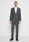 Grauer, maßgeschneiderter Anzug mit schmaler Passform, Ein-Knopf-Blazer und flachen Vorderhosen. Darunter ist ein knitterfreies weißes Hemd sichtbar. Polierte schwarze Schuhe.