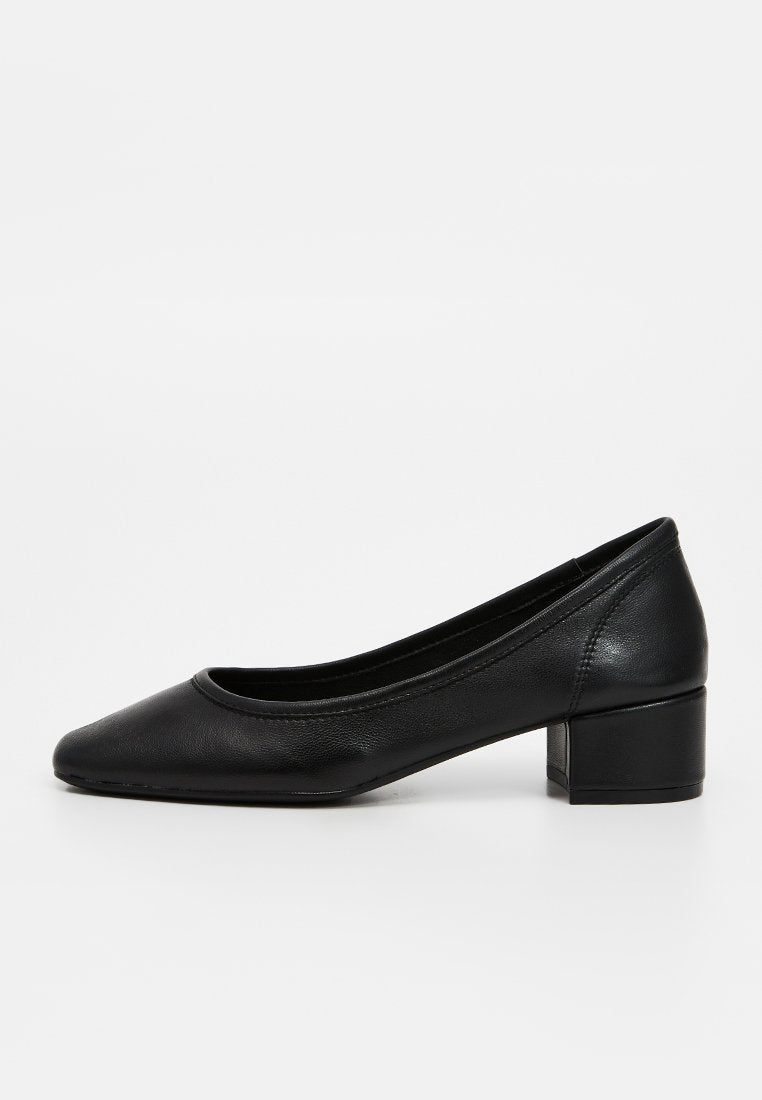 Schwarze Lederflache Schuhe mit abgerundeter Spitze, glatter Textur und minimalistischem Design, ausgestattet mit einem Blockabsatz für Stabilität.