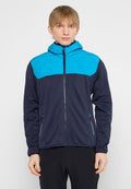 Junge Person in einer marineblauen und leuchtend blauen Zip-Jacke mit Kapuze, die vor einem schlichten hellen Hintergrund steht.