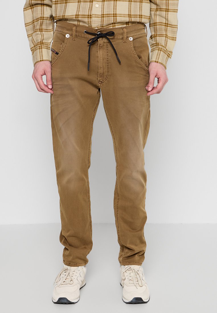 Braune, schmal geschnittene Hose mit einem Bindegürtel und Seitentaschen, die eine glatte, leicht ausgewaschene Textur und ein lässiges Design aufweist.