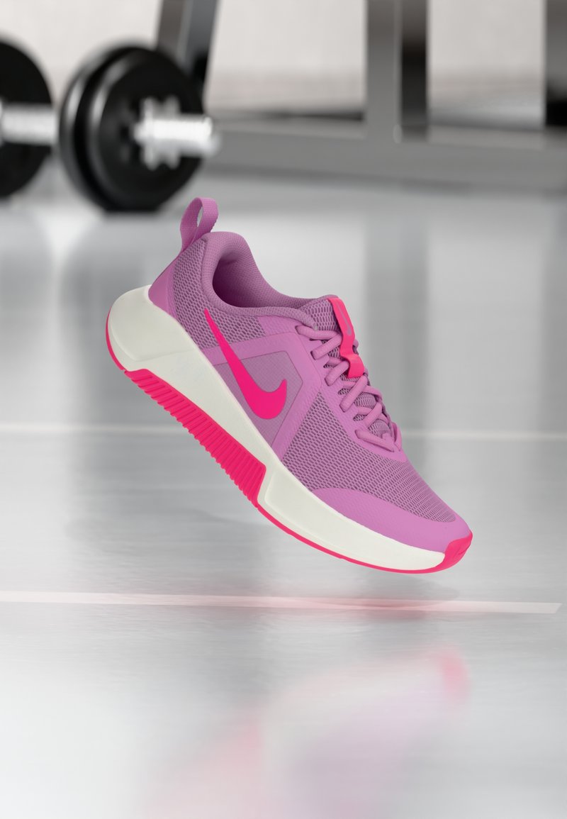 Lila Sportschuh mit Mesh-Obermaterial, pinken Akzenten und weißer Zwischensohle. Verfügt über eine strukturierte Außensohle und ein deutlich sichtbares pinkes Nike-Swoosh.