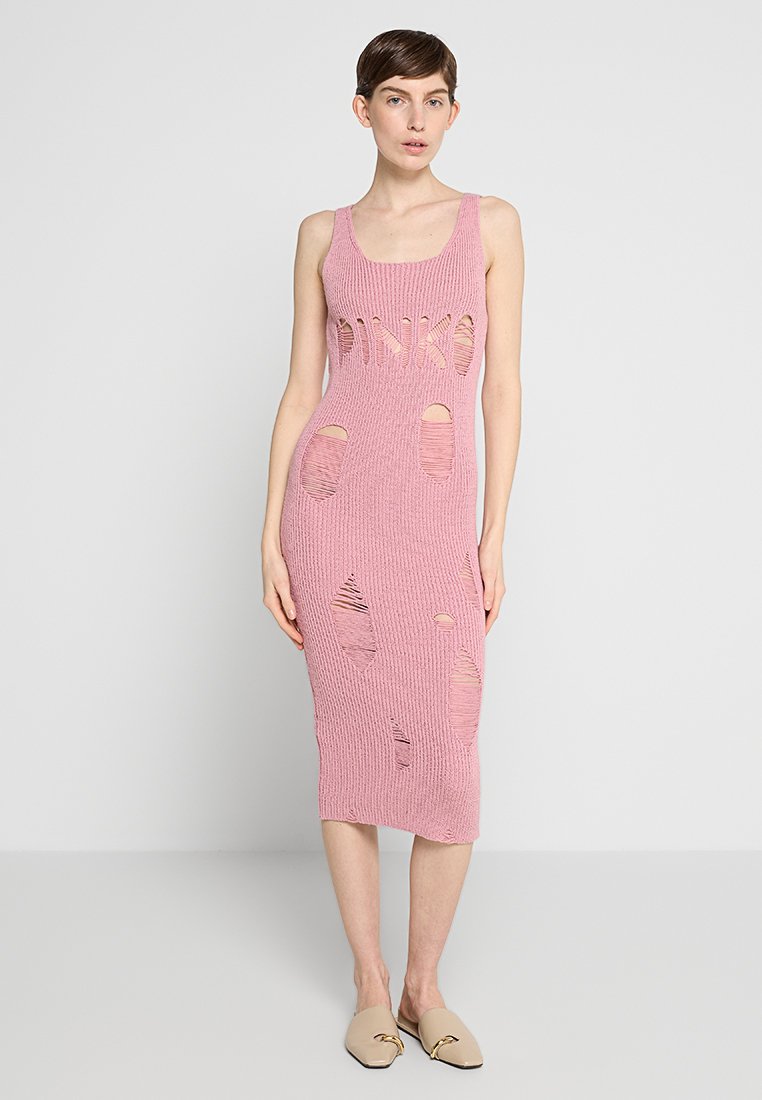 Rosa gestricktes Midikleid mit unterschiedlichen Lochmustern, im Tanktop-Stil. Das Modell trägt helle Slippers, die eine figurnahe Silhouette zur Geltung bringen.