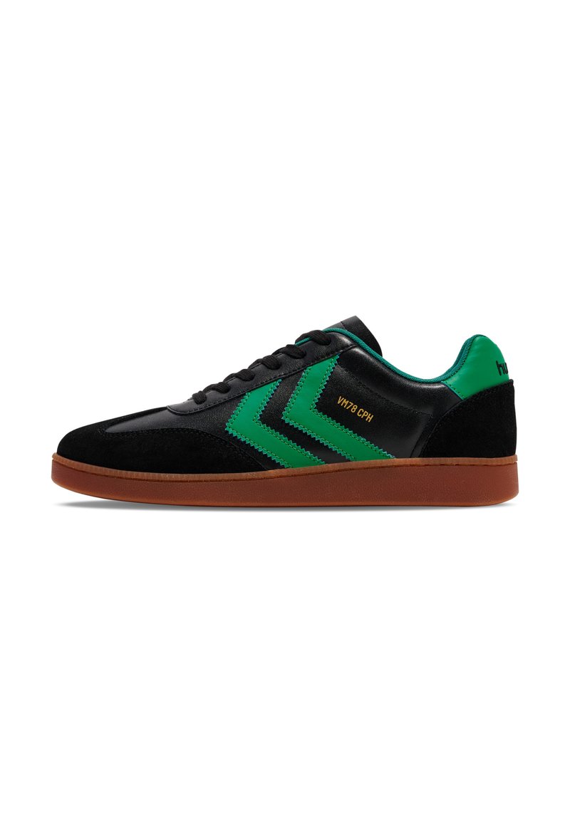 Schwarze und grüne Sneaker aus Wildleder und synthetischem Leder, mit Chevron-Mustern und einer braunen Gummisohle. Goldene Schrift an der Seite.