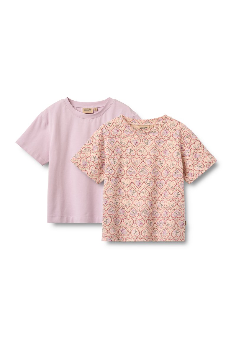 Zwei kurzärmelige Kinder-T-Shirts, eines einfarbig helllila und das andere beige mit pinkem und violettem Herzmuster, flach auf weißem Hintergrund ausgelegt.