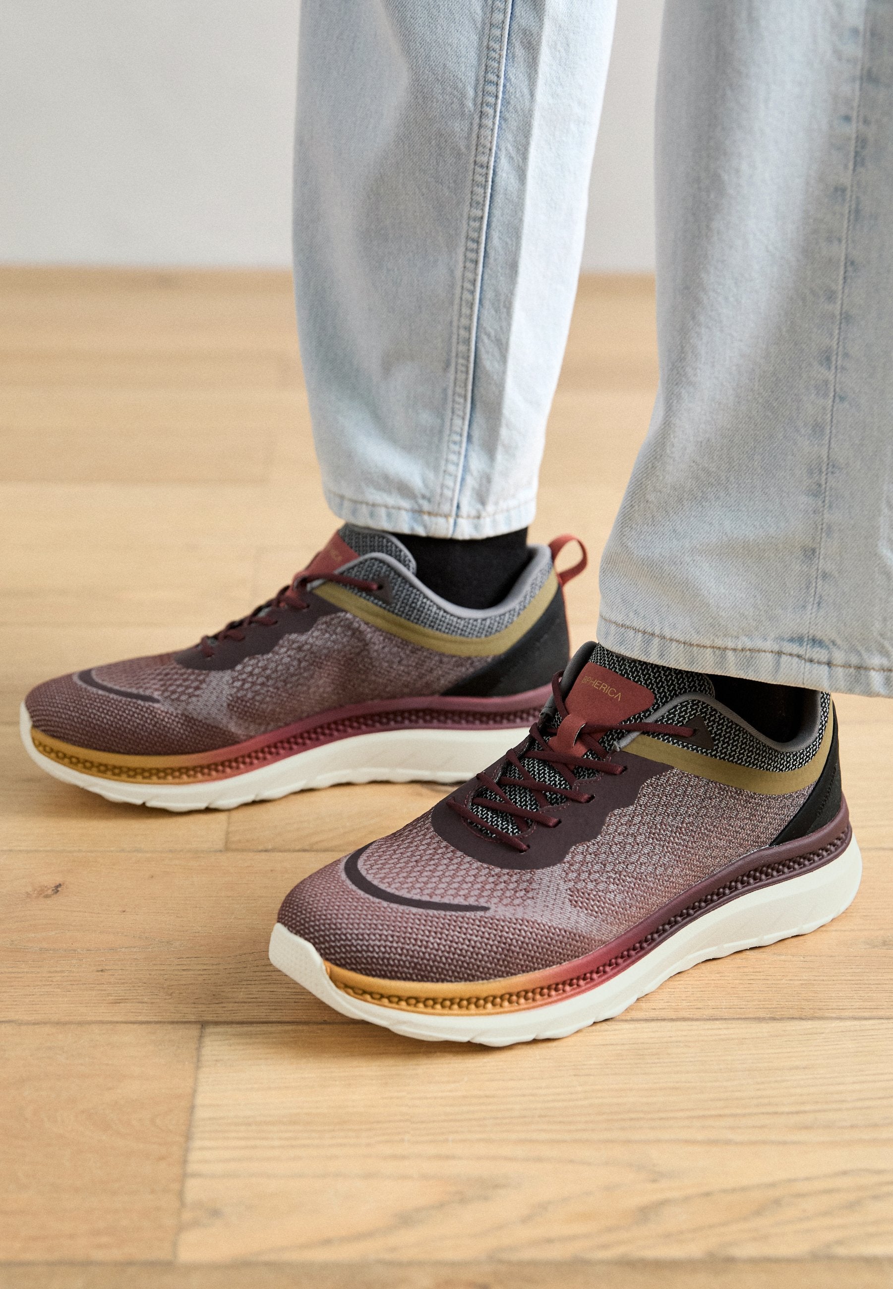 Sportliche Schuhe mit einem Stricknetzdesign in Burgunderrot und Grau, schwarzen Akzenten, weißer Sohle und verstellbaren schwarzen Schnürsenkeln.