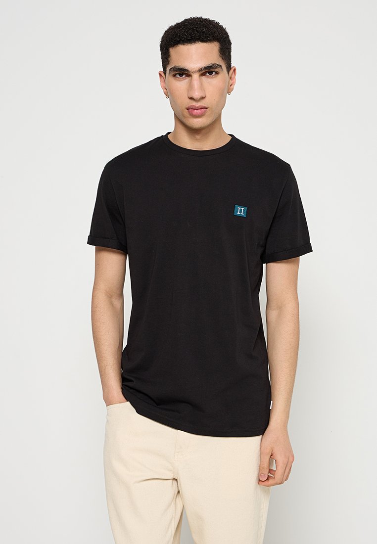 Schwarzes Baumwoll-T-Shirt mit Rundhalsausschnitt, kurzen Ärmeln und einem gestickten türkisfarbenen Logo auf der linken Brust; glatte Textur und lockere Passform.