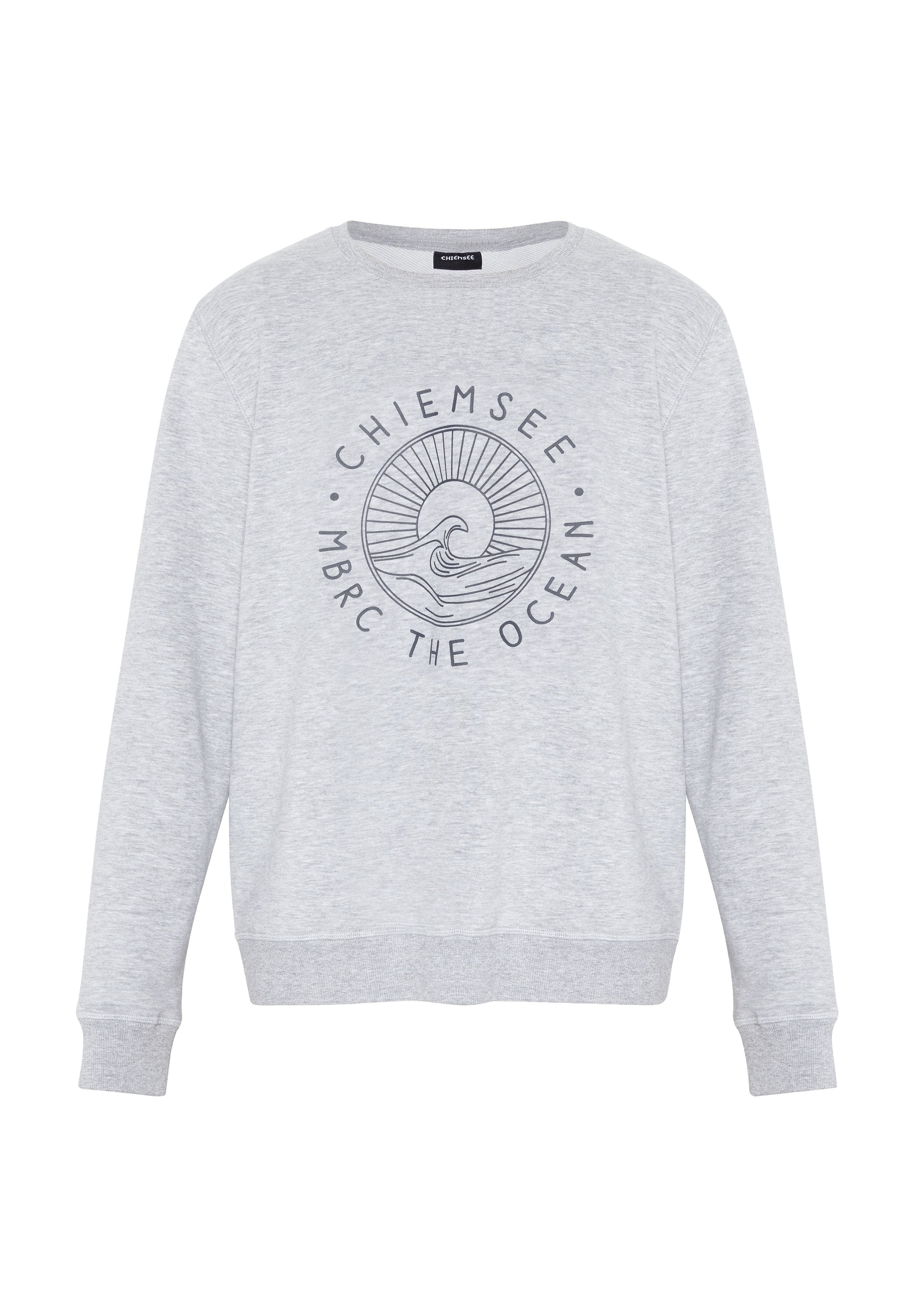 Hellgraues Sweatshirt mit Rundhalsausschnitt und langen Ärmeln, mit einem kreisförmigen Wellen- und Sonnendesign und dem Text "Chiemsee MBRC The Ocean" auf der Vorderseite.